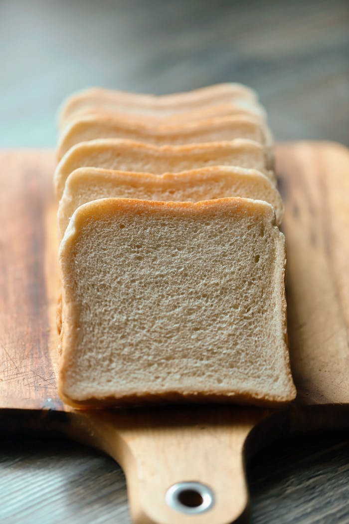 services-03 Freshly sliced white bread arranged on a wooden board for breakfast.